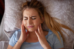 woman-clenching-teeth-in-bed-bruxism-Jan-blog