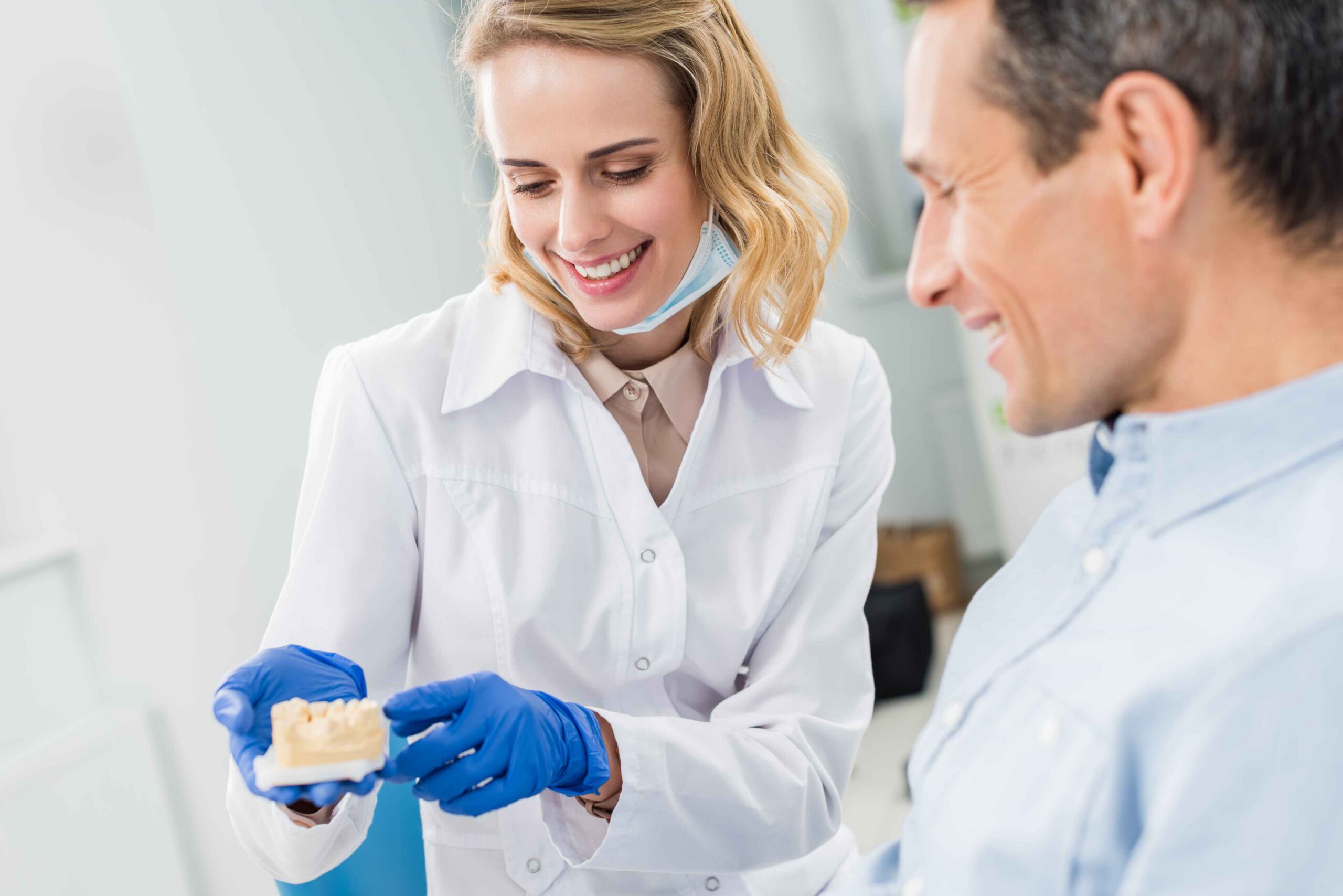 Dentist explaining a dental model to a smiling patient.